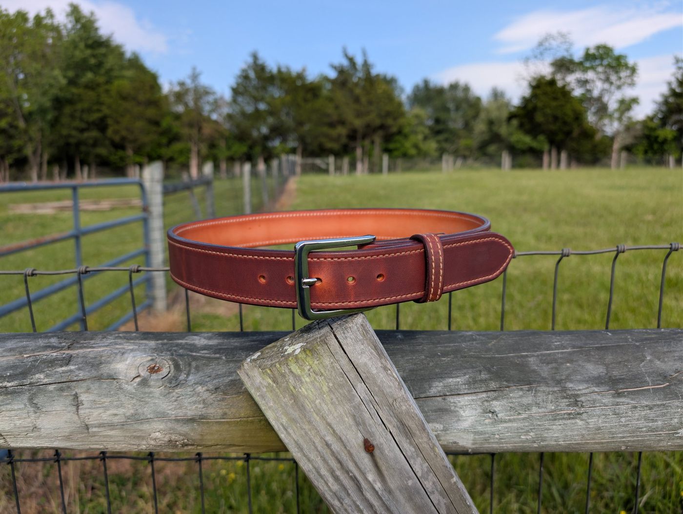 Plain brown leather belt on a fence post