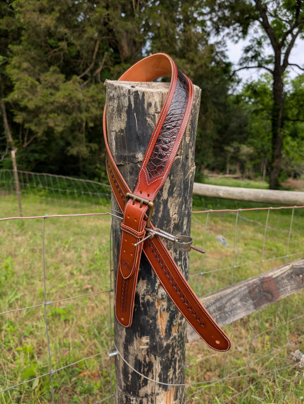 Tooled leather belt draped on a fence post