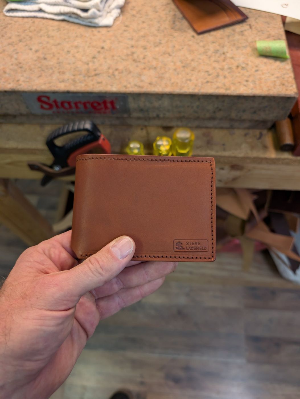 Brown leather bifold wallet with maker's mark
